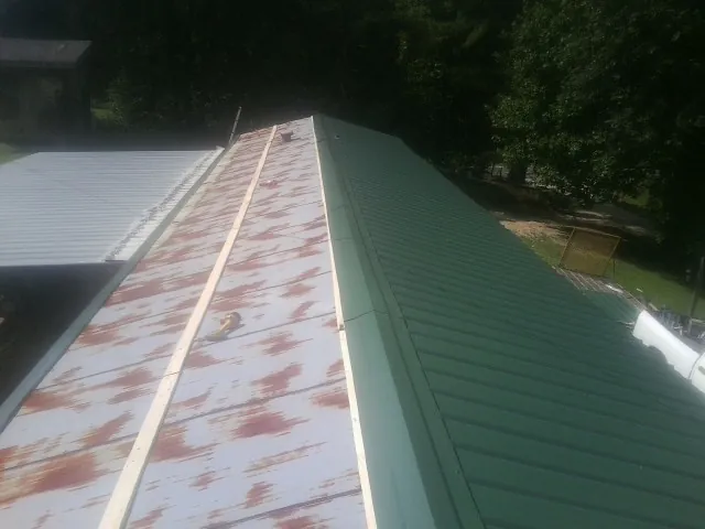 Old rusted panels beside newly installed green metal roofing — Wind Damage Roof Repair by Roofing Brothers in Sand Lake