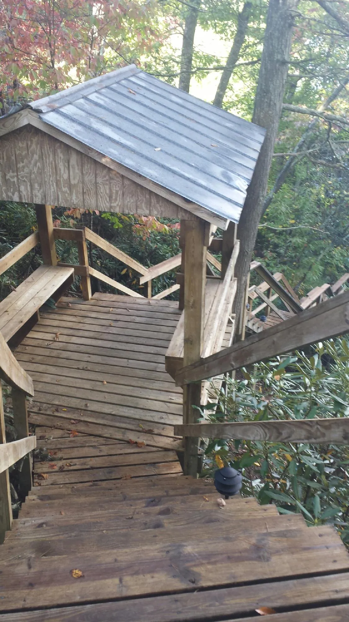 Metal roofed shelter over wooden steps on a wooded walkway — Skylight Repair & Installation work by our crew in Sand Lake