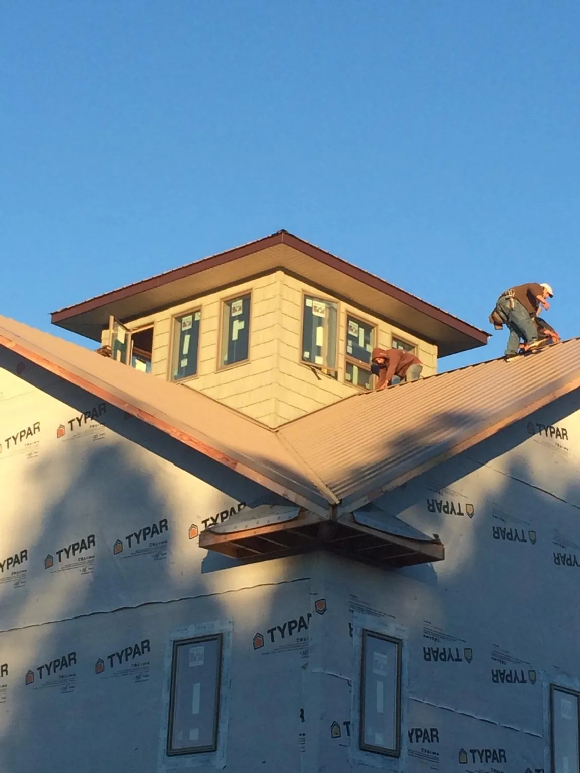 Roofers working around a rooftop cupola on a new metal roof at sunset — Roof Waterproofing in Sand Lake by Roofing Brothers
